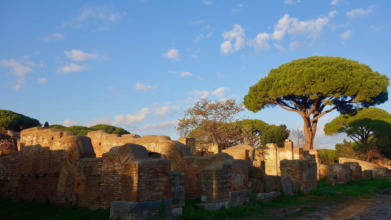 Rovine in mattoni di Ostia antica tra i pini, sotto il cielo azzurro