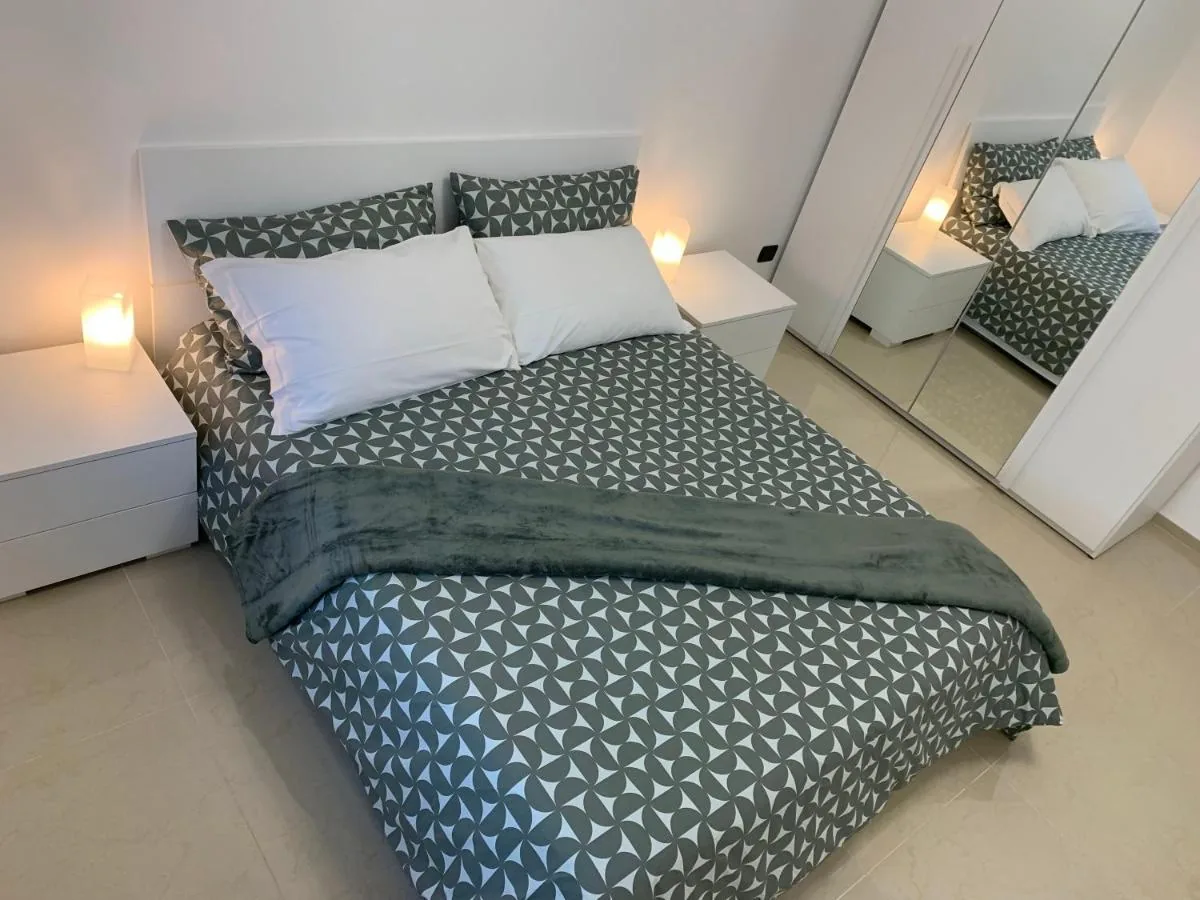 Il letto matrimoniale con il copriletto verde a motivi geometrici e l’armadio a specchio