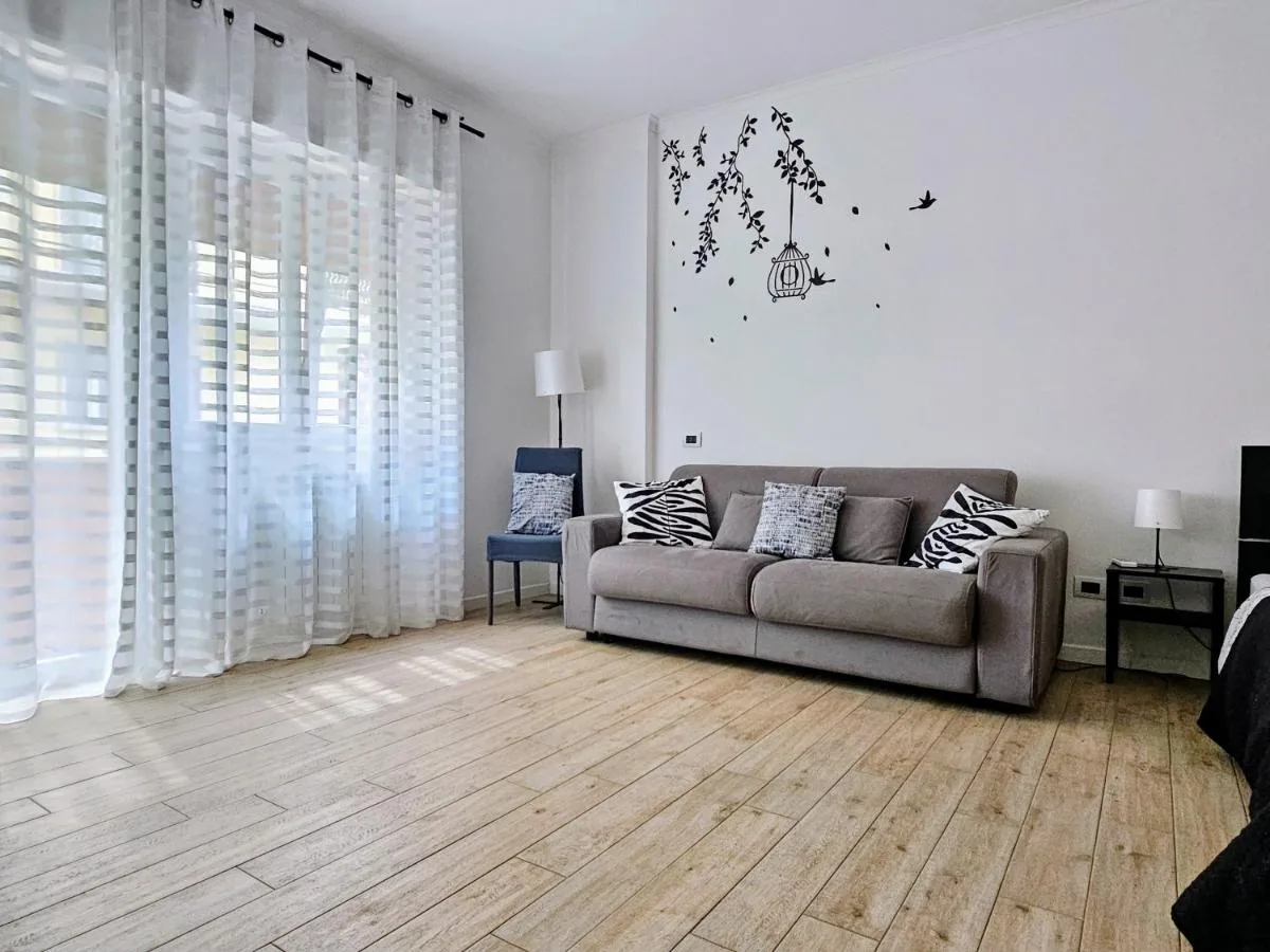Maremè Guest House — La zona giorno con il divano, la poltrona e le finestre luminose
